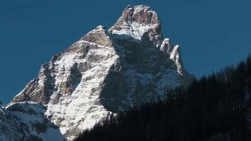 Aerial view with smooth motion showing the Matterhorn's snowy peak, descending to Cervino Ski Paradise and Cervino town in a rugged alpine valley. video