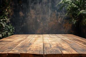 A rustic wooden table stage for product with a textured surface, set against a dark, weathered wall. Lush green plants frame the scene, adding a natural touch to the environment. photo