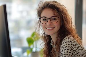 A woman with glasses sitting at a desk photo