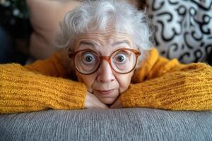 An older woman with glasses and a yellow sweater laying on a couch photo