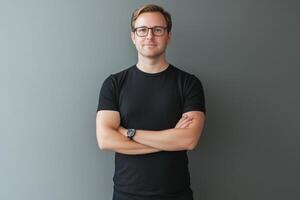 Portrait of a young man with glasses standing in front of gray background photo
