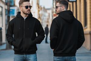 Two men wearing black hoodies standing on a street photo