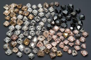 A collection of various gemstones arranged in a visually appealing pattern. The stones include clear, pink, brown, and black diamonds, showcasing their unique shapes and colors. photo