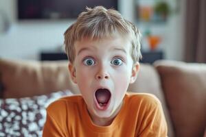 A young boy is making a surprised face while sitting on a couch photo