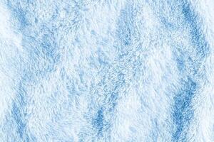 Seamless texture of soft, fluffy blue towel fabric, resembling fur or fleece. The surface appears plush and inviting, with varying shades of blue creating a gentle, soothing effect. photo