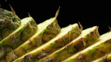 Slices of pineapple gyrating on black background, studio video