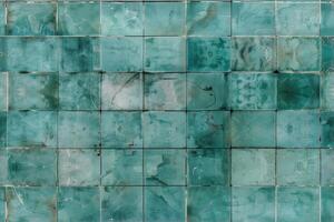 A textured surface composed of square tiles in varying shades of teal and green, some tiles showing signs of wear and discoloration, creating an abstract pattern. photo