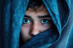 A young boy peeking out from under a blanket photo