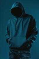 A man in a hoodie standing in front of a blue background photo