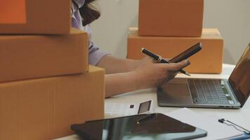 A woman is using her laptop and a cell phone while sitting in front of boxes video