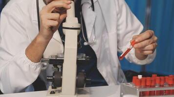A man in a lab coat is looking at a test tube video