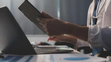 A doctor is using a tablet computer while sitting at a desk video