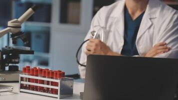 A doctor is working on a laptop in front of a microscope video