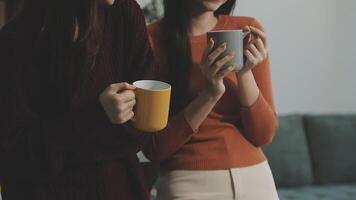 Two women holding coffee cups in front of a couch video