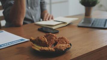 A man sits at a desk with a plate of fried chicken and fries video