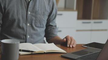 Man sitting at desk with laptop and notebook video