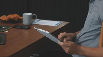 Man using tablet at desk with laptop and coffee video