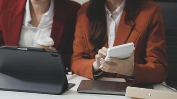 Two businesswomen in suits sitting at a table with their laptops video