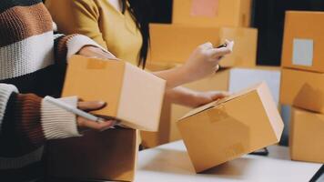Two people are holding boxes and one is using a laptop video
