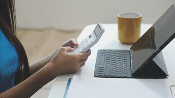 A woman is using a calculator and a laptop video