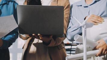 Three people holding laptops and papers while standing in front of a building video