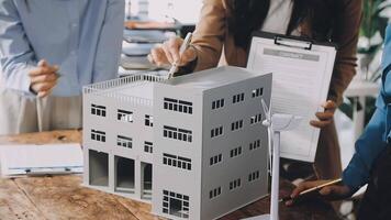Three people are looking at a model of a building video