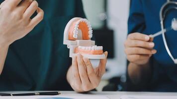 A dentist and a patient holding a model of a tooth video