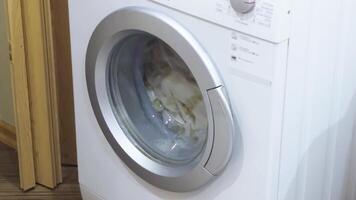 A washing machine in action with visible rotating laundry behind the glass video
