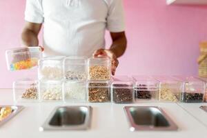 An ice-cream parlor worker is preparing all the toppings for the day on the counter photo