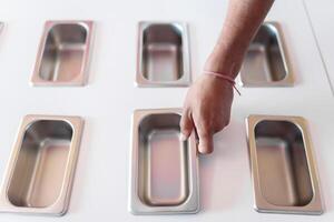 A hand of an ice-cream parlor worker is placing a clean metal tray photo