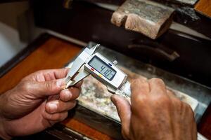 Jeweler hands measuring and checking gold jewel size with vernier caliper tool. Goldsmith working creating in his jewelry workshop. photo