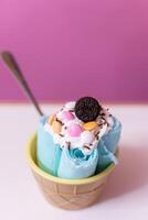 Close up of a blue rolled ice cream decorated with chocolates, cream and a cookie photo