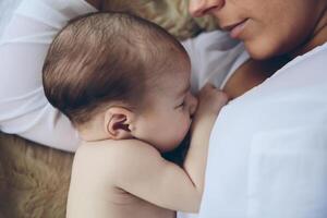 Newborn lying on the bed embraced by her mother photo