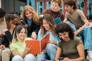 Delighted multiracial students reading notes and smiling on stairs photo