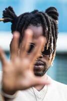 Trendy guy with dreadlocks covering face with palm photo
