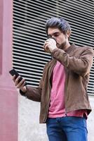 Man drinking takeaway coffee and browsing smartphone photo