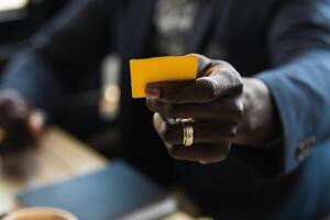 Anonymous crop black executive with business card in cafe photo
