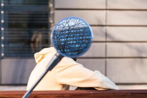 Person covered with rearview mirror sitting on bench photo