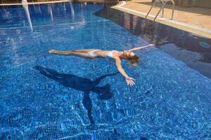Female chilling while floating in pool water photo