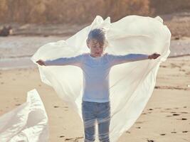 Calm boy rolled in plastic film with stretched hands aside photo