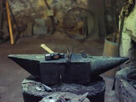 Anvil with hammer and tongs in forge photo