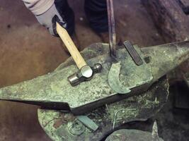 Crop forger working on anvil with hammer and sickle photo