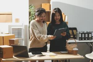 Two women standing in front of a desk with a laptop photo