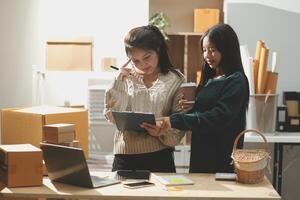 Two women standing in front of a desk with boxes and papers photo