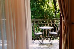 View from the window to the terrace with a table and chairs on it photo