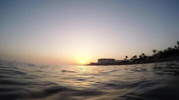 Man floating in a calm beach at sunset in slow - First person view - Loop video