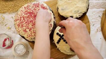 the last steps in creating easter cake. skilled hands carefully add the finishing touches, bright pink sugar crystals, a composition of blueberries, almonds and sprigs of rosemary. Close up, top view video