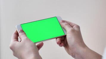POV play smartphone with green screen on white isolated background close-up in female hands. Modern technology in real life video