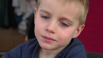A close-up of a 4-year-old boys face shows his intense focus as he gazes at something. He then takes a bite of a sweet bun, savoring the moment, with a close-up of his mouth chewing the delicious video