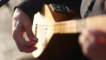 Strumming a wooden string instrument in a sunny park setting video